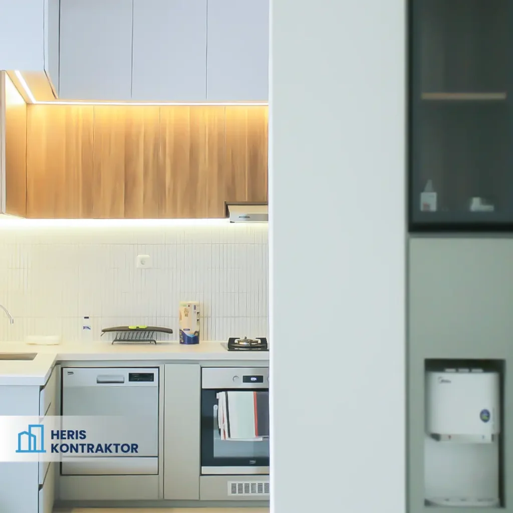 Detail Dapur Minimalis berwarna putih jika dilihat dari luar, sebagian dapur terekspos keluar dan sebagian lagi bersembunyi dibalik partisi menyerupai tembok dengan kulkas tanam