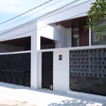 Rumah modern minimalis dengan pagar hitam dan dinding roster setelah renovasi total.