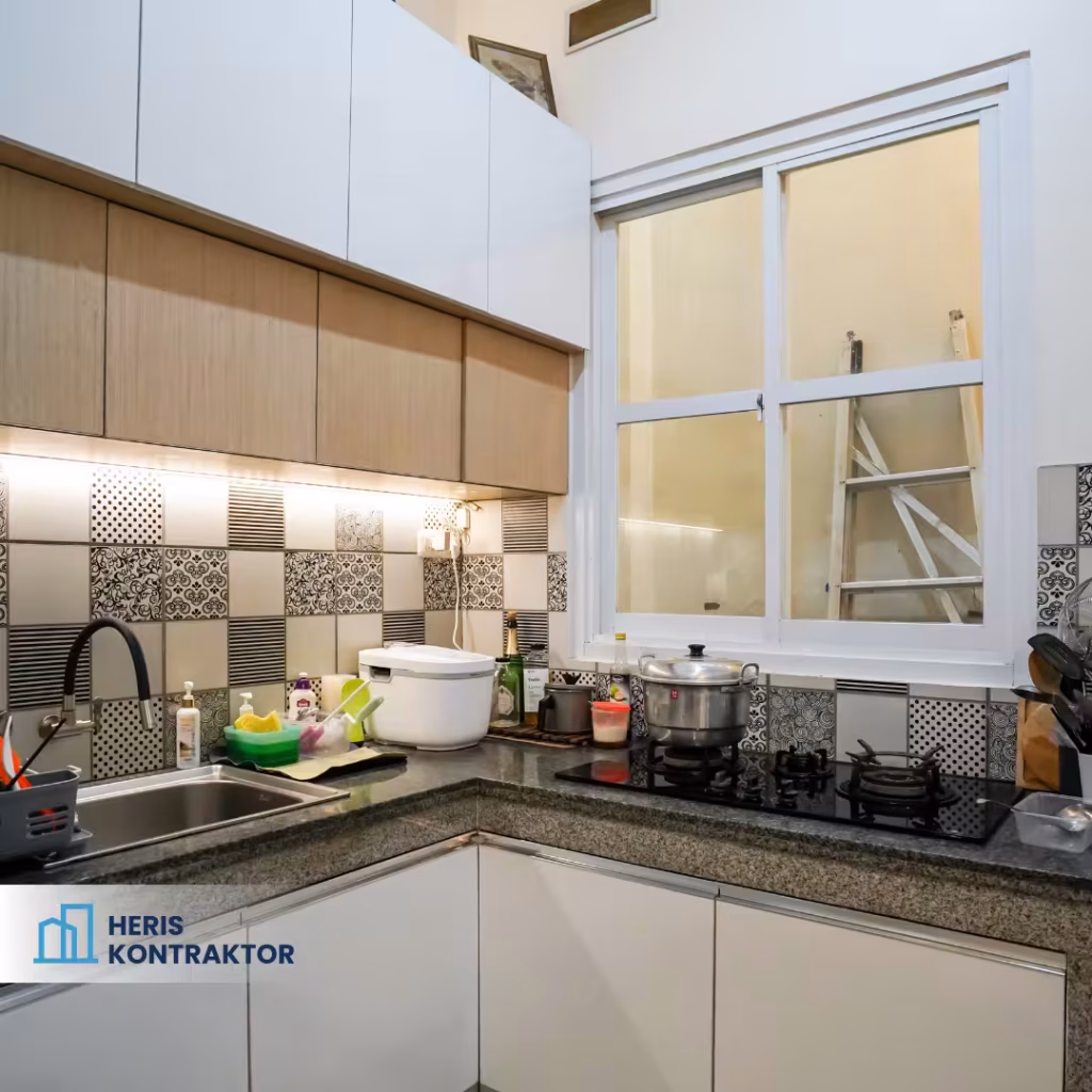 Dapur dengan area memasak, wastafel, dan pemandangan jendela yang terang, serta backsplash motif kotak hitam putih.