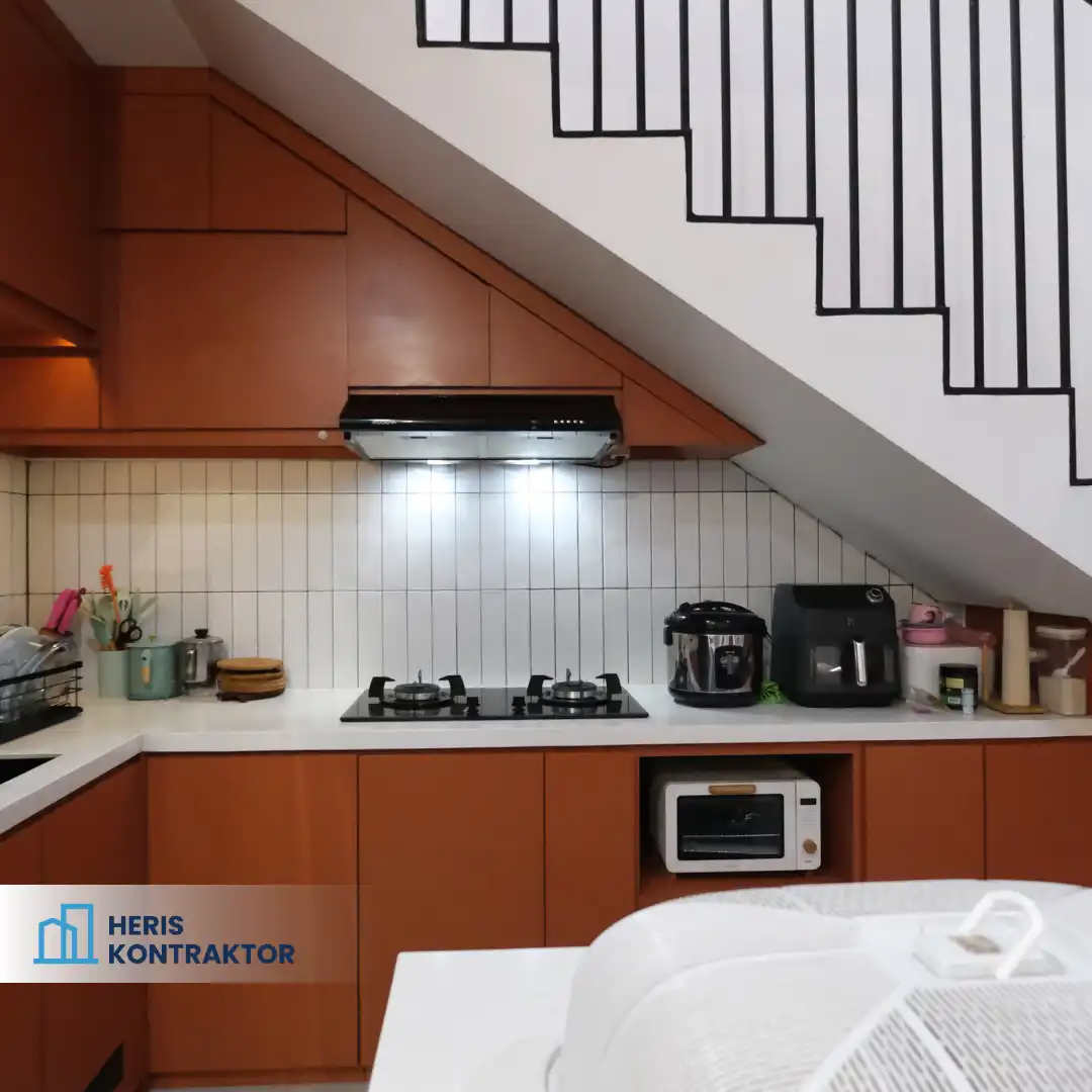 Dapur dengan kabinet kayu dan kompor, serta tangga modern di bagian atas.