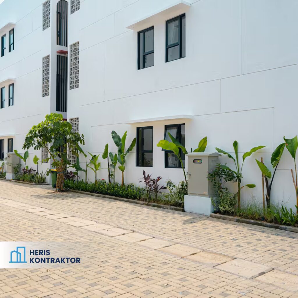 Area samping kost modern Bogor dengan jendela hitam minimalis dan taman kecil dengan tanaman hias tropis.
