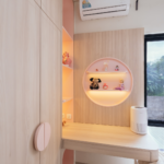 Area meja belajar kamar anak perempuan dengan rak circular pink berlampu LED, open shelf built-in kayu, lemari pakaian dengan handle bulat, dan air purifier di sudut