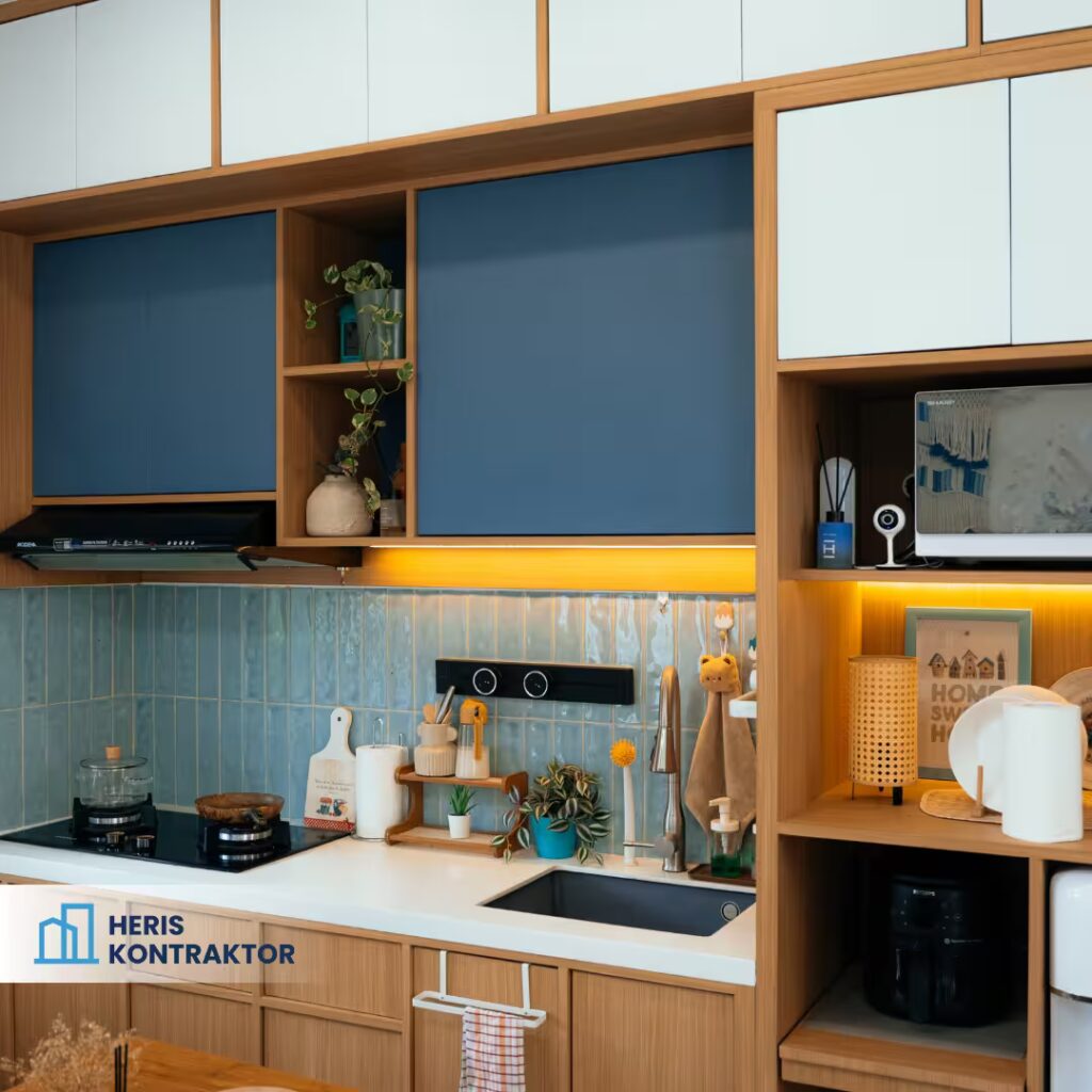 Detail area masak dan cuci dapur modern dengan backsplash keramik biru, kabinet kayu, dan underlighting kuning