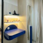 Area meja belajar melayang biru dan rak display LED kamar anak laki-laki, tampak samping lemari dengan cermin lengkung dan gorden krem di sebelahnya
